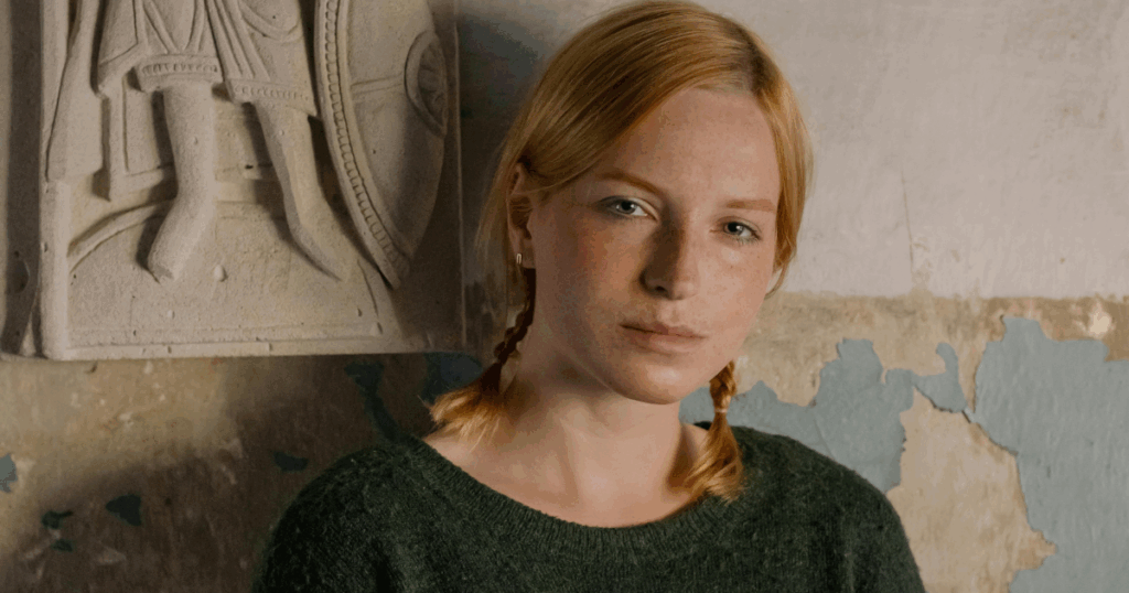 Pristiq withdrawal symptoms: Portrait of a young woman with red hair in braids, standing near a stone carving.