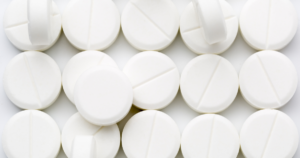 - Bakersfield Recovery Center Pile of white round tablets with a shallow score line scattered across a light background, suggesting medicine pills used for distribution or storage.