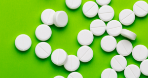- Bakersfield Recovery Center White round tablets scattered on a bright green background.