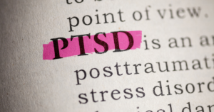 Close-up of a dictionary page with the acronym PTSD highlighted in pink ink.
